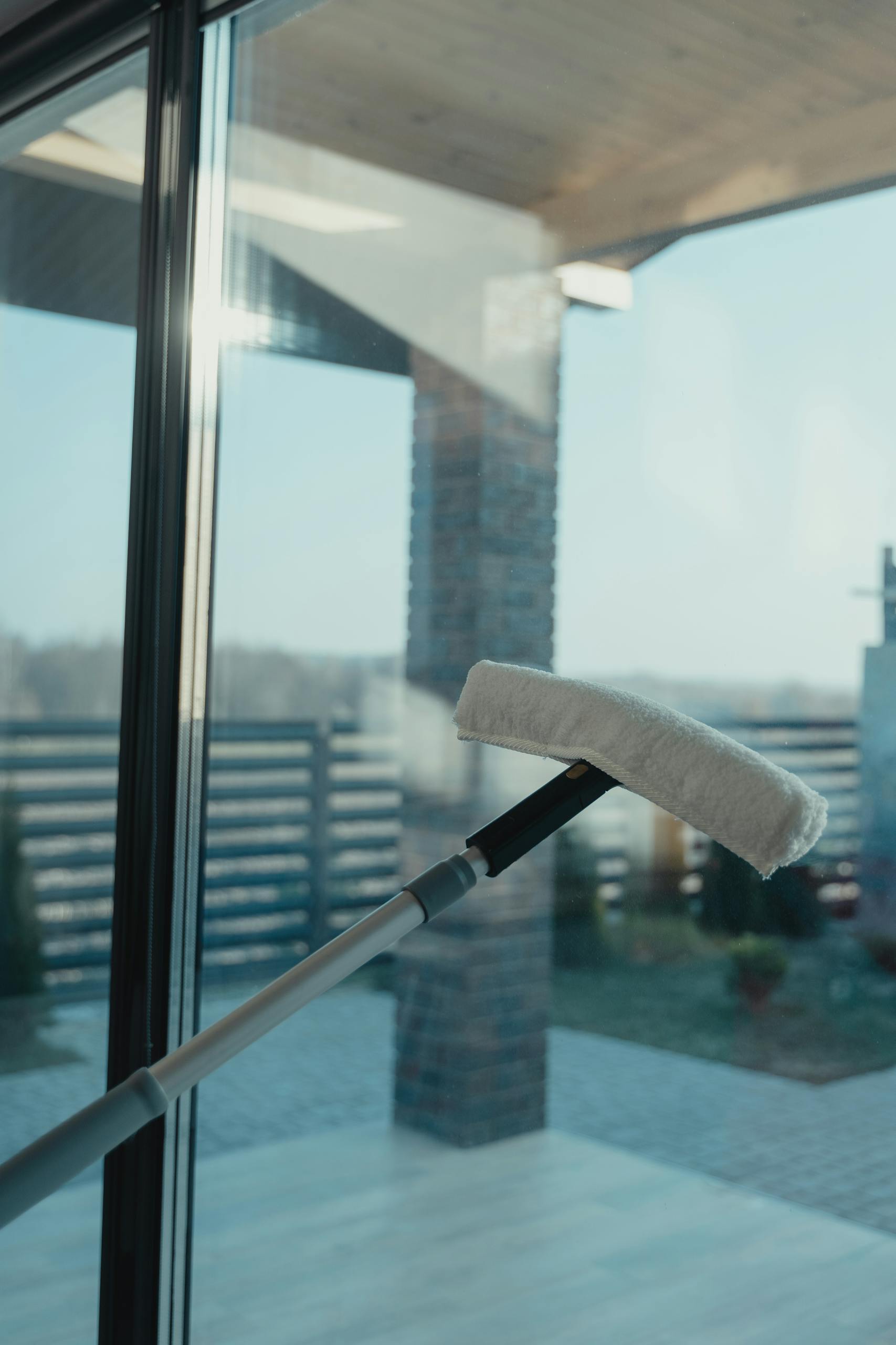 A modern cleaning tool used to clean a large glass window with a clear outdoor view.