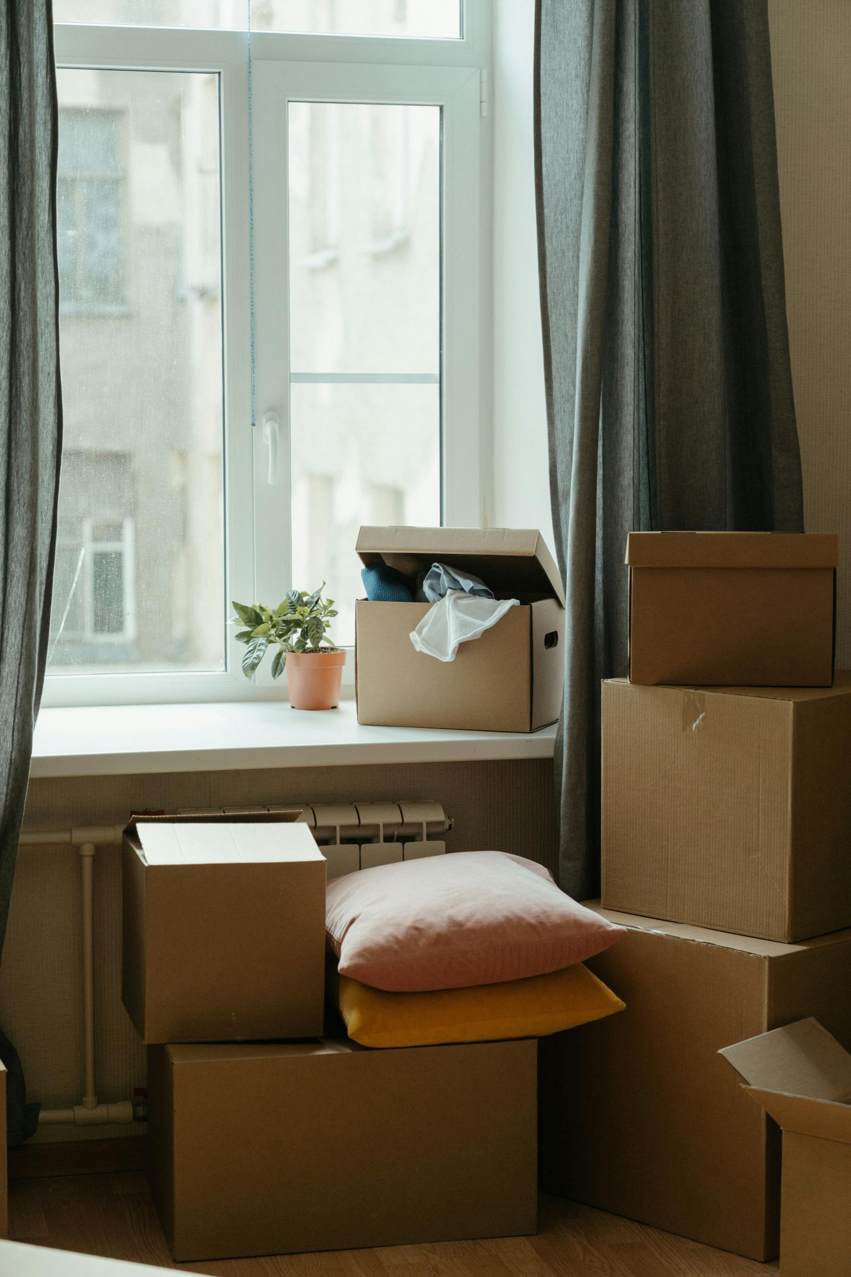 Stack of moving boxes in a sunlit room, symbolizing a fresh start in a new apartment.